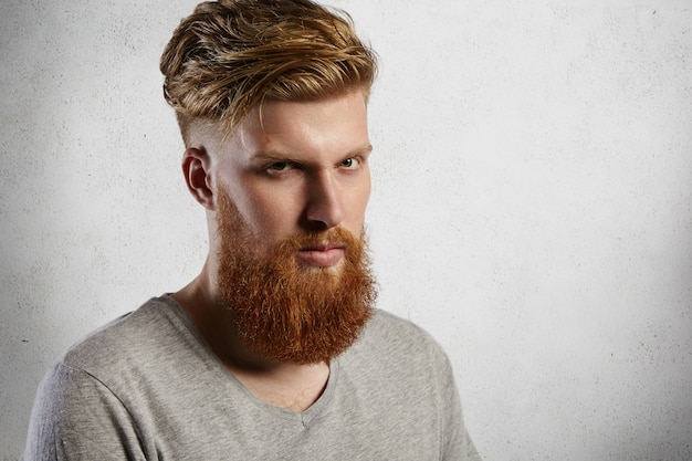 Portrait d'un homme en colère maussade avec une barbe hipster floue habillé avec désinvolture avec une expression de visage grave et sévère, démontrant sa masculinité.