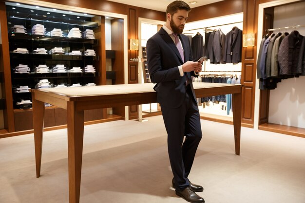 Portrait de l'homme en costume à l'aide de smartphone