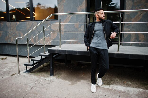 Portrait d'un homme élégant à la barbe arabe portant un col roulé gris et un jaket noir