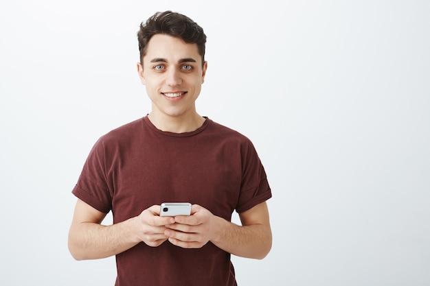 Portrait d'un homme européen heureux impressionné en tenue décontractée avec smartphone