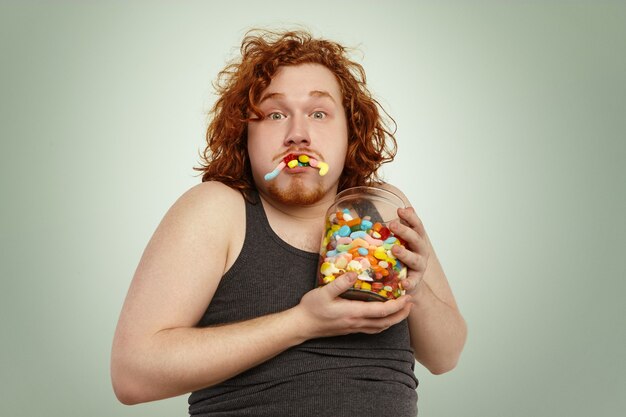 Portrait d'un homme européen rousse drôle bourrant la bouche avec des marmelades