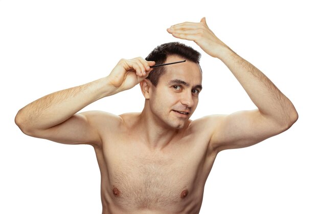 Portrait d'un homme faisant une coiffure se brosser les cheveux isolé sur fond de studio blanc