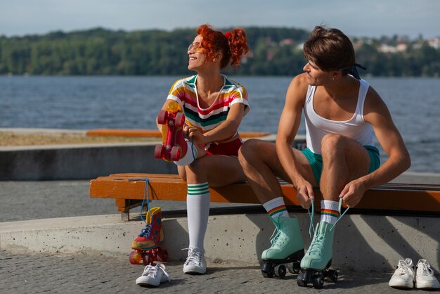 Portrait d'homme et de femme à la plage avec des patins à roulettes dans l'esthétique des années 80