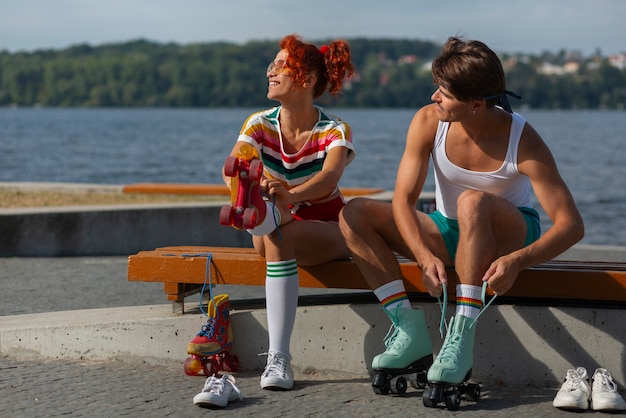 Portrait d'homme et de femme à la plage avec des patins à roulettes dans l'esthétique des années 80