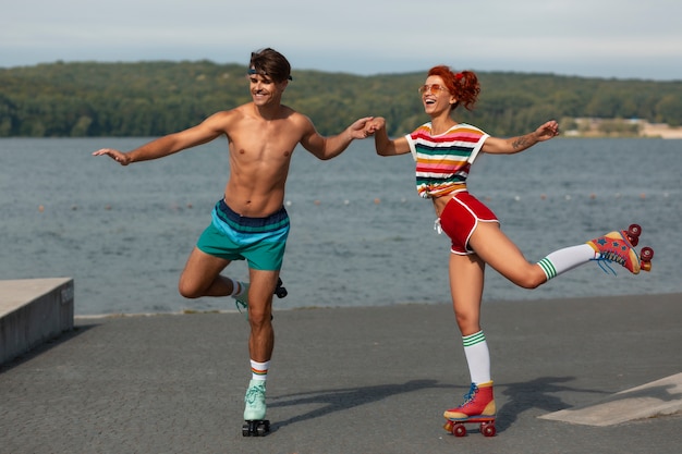 Portrait d'homme et de femme à la plage avec des patins à roulettes dans l'esthétique des années 80