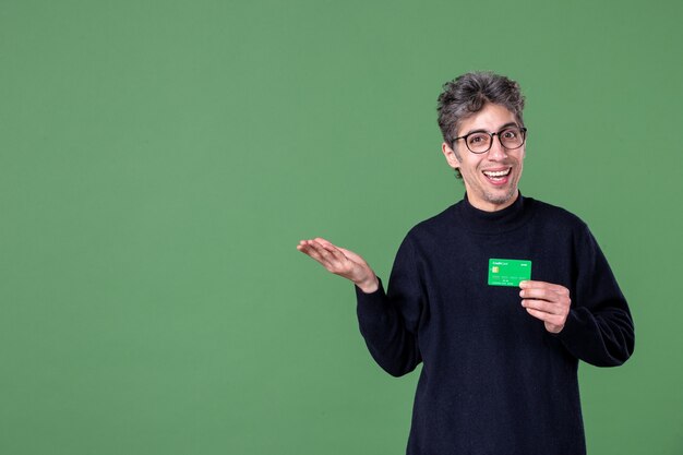 Portrait D'un Homme De Génie Tenant Une Carte De Crédit Verte Dans Un Mur Vert Tourné En Studio