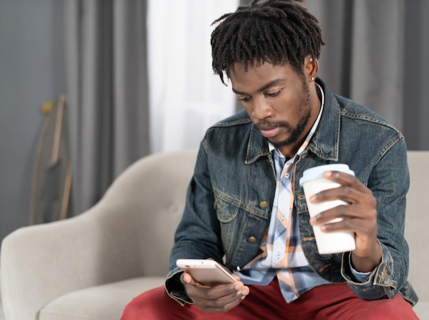 Portrait d'un homme heureux ayant une conversation actuelle assis sur le canapé Concept de médias sociaux