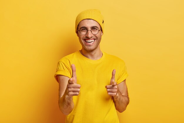 Portrait d'homme heureux pointe les doigts avant à la caméra, vous choisit, regarde volontiers la caméra, sourit largement