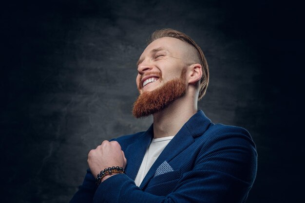 Portrait d'homme hipster rousse barbu vêtu d'une veste bleue sur fond gris.