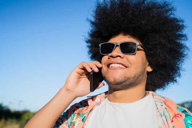 Portrait d'un homme latin afro parlant au téléphone tout en se tenant à l'extérieur dans la rue