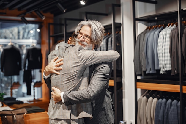 Portrait d'un homme mûr. Assistant aide un client. Senior visitant une boutique de mode. Les hommes achètent un nouveau costume exclusif.