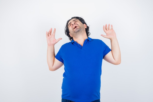 Portrait d'homme mûr le bâillement et l'étirement du haut du corps en t-shirt bleu et à la vue de face endormie