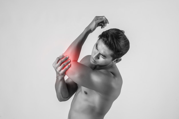 Photo gratuite portrait d'un homme muscle ayant des douleurs au coude isolé sur fond blanc