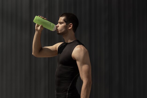 Portrait homme musclé faisant une pause pour hydrater son corps après l'entraînement.