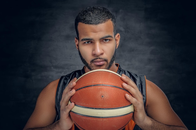 Le portrait d'un homme noir barbu tient un ballon de basket.