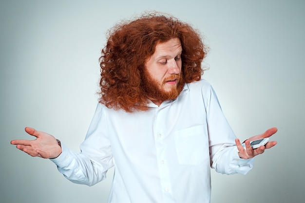 Portrait d'homme perplexe parlant au téléphone un fond gris