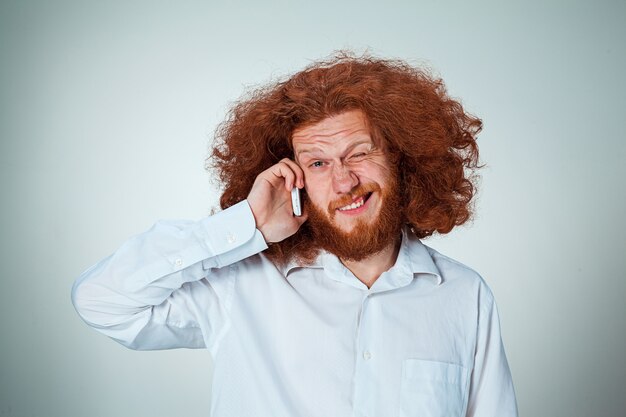 Portrait d'un homme perplexe parlant au téléphone un fond gris