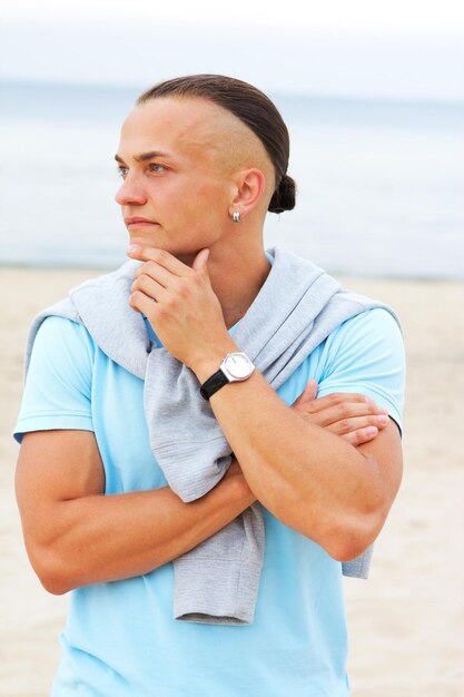 Portrait d'homme sur la plage en t-shirt bleu