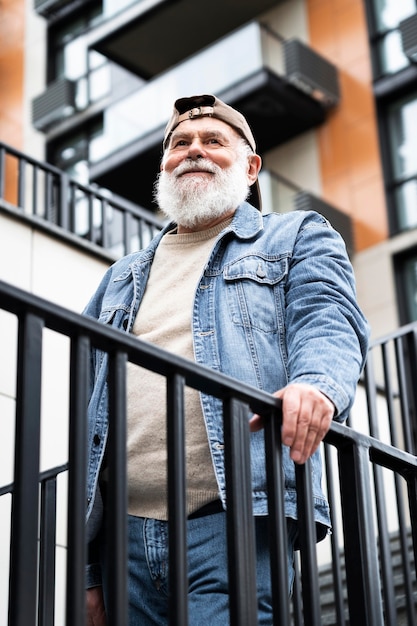 Portrait d'un homme plus âgé posant dans les escaliers à l'extérieur de la ville