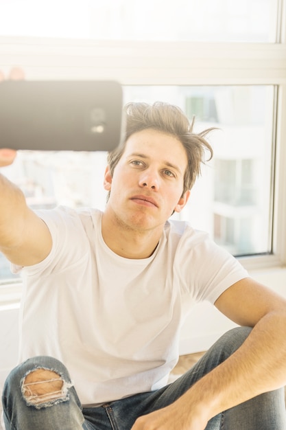 Photo gratuite portrait d'un homme prenant selfie avec téléphone intelligent