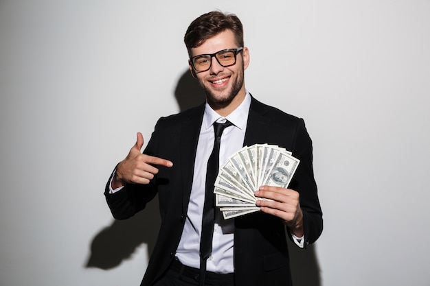 Portrait d'un homme qui réussit souriant en costume et lunettes