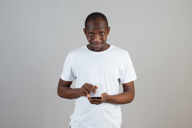 Portrait d'homme regardant un téléphone portable sur un mur gris