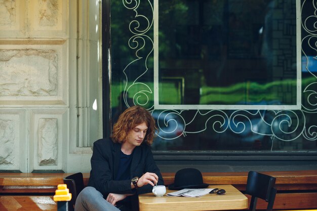 Portrait homme rougeâtre intéressant mélanger le café à l'extérieur