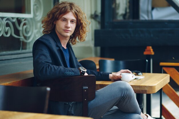 Portrait homme rougeâtre intéressant posant avec du café