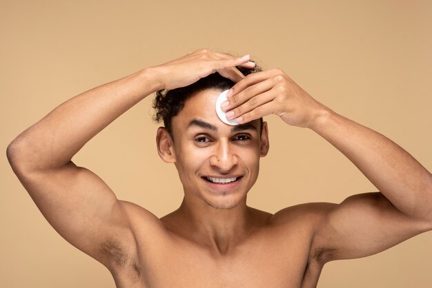 Portrait d'un homme s'essuyant le visage avec un tampon de maquillage