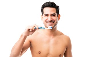 Photo gratuite portrait d'un homme séduisant tenant une brosse à dents en souriant en studio