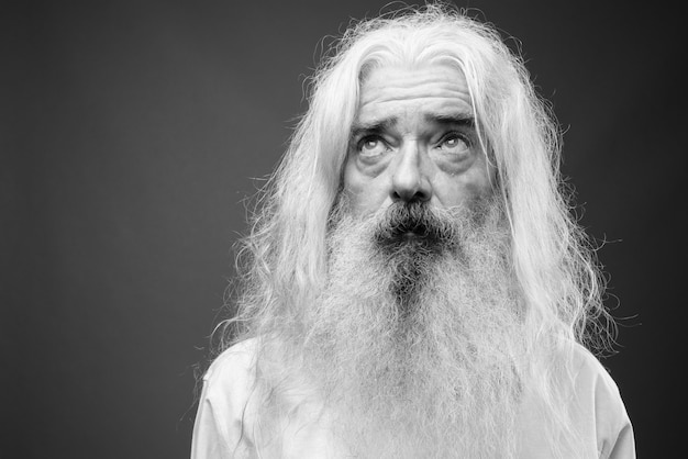 Portrait d'homme senior aux cheveux longs et à la barbe sur gris en noir et blanc