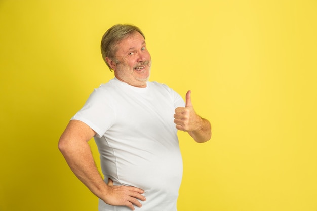 Portrait de l'homme senior caucasien isolé sur studio jaune