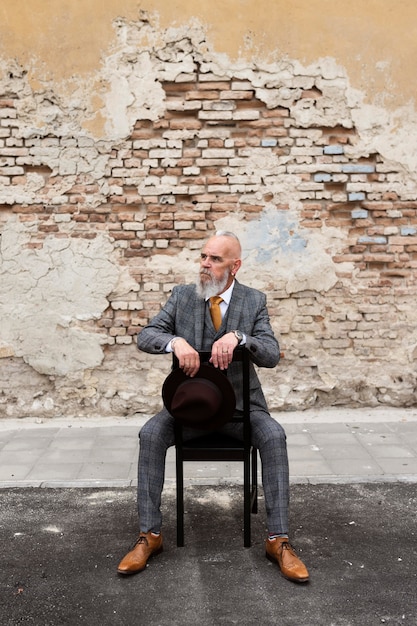 Portrait d'un homme senior élégant assis à l'extérieur