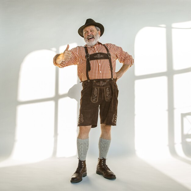 Portrait d'homme senior de l'Oktoberfest au chapeau, portant les vêtements traditionnels bavarois. Mâle pleine longueur tourné en studio sur fond blanc. La célébration, les vacances, le concept du festival. Bon appel.