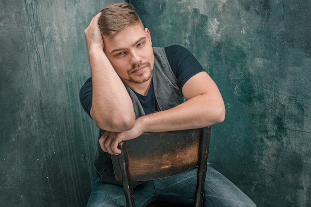 Portrait d'homme sérieux assis sur la chaise en studio