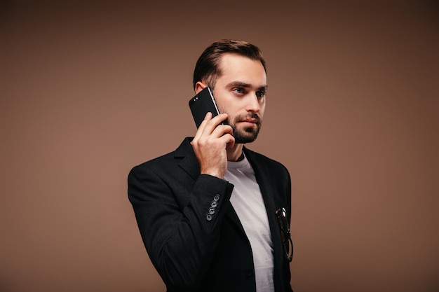 Portrait d'un homme sérieux en costume noir parlant au téléphone