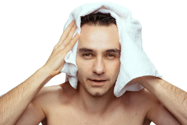 Portrait d'homme avec une serviette de bain blanche après la douche isolée sur fond de studio blanc