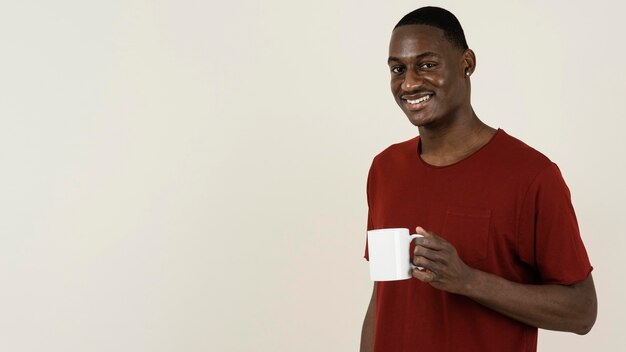 Portrait d'homme souriant dans un t-shirt tenant une tasse avec espace copie