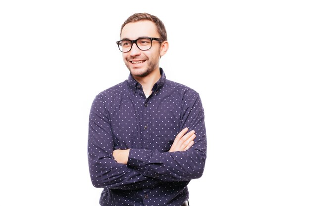 Portrait d'un homme souriant debout, les mains croisées sur un mur gris