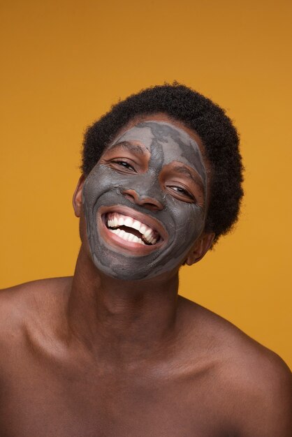 Portrait d'un homme souriant avec un masque au charbon sur son visage