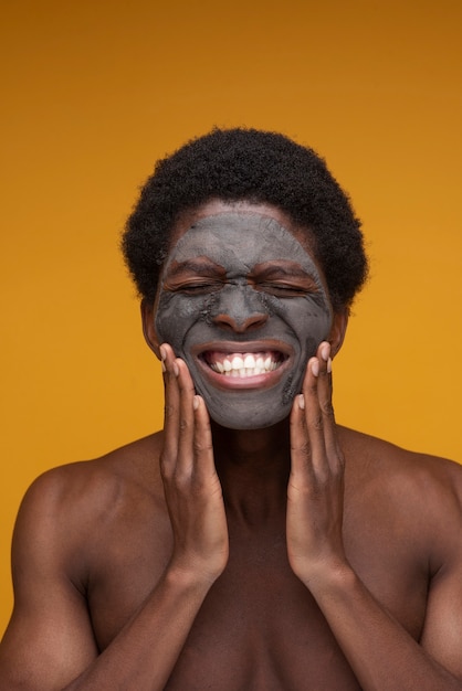 Photo gratuite portrait d'un homme souriant avec un masque au charbon sur son visage