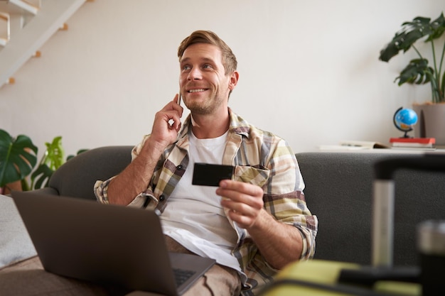 Photo gratuite portrait d'un homme souriant réservant un hôtel confirmant l'achat par téléphone tenant une carte de crédit