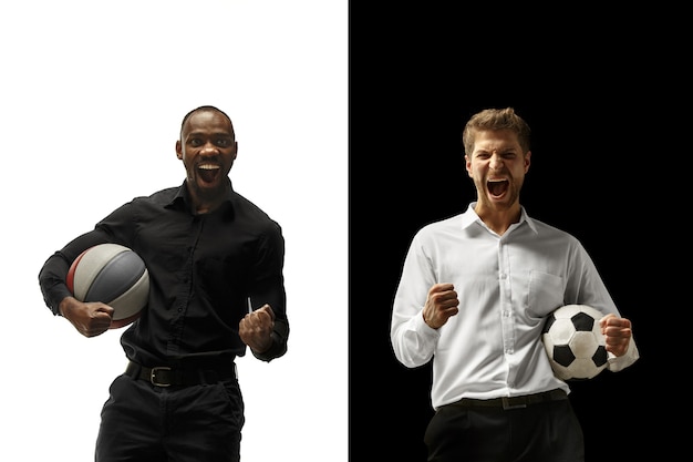 Portrait d'un homme souriant tenant un ballon de football et de basket-ball isolé sur fond blanc et noir. Le succès des hommes afro et caucasiens heureux. Couple mixte.