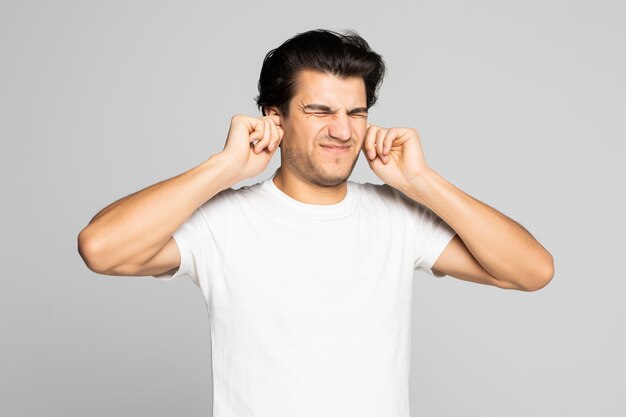 Portrait d'un homme en t-shirt blanc couvrant ses oreilles