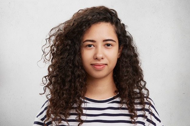 Portrait horizontal de race mixte bouclés belle femme aux yeux sombres et lèvres charnues habillé avec désinvolture, être délicieux