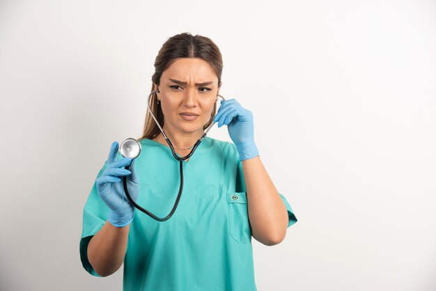 Portrait d'une infirmière sérieuse avec des gants en latex et un stéthoscope.