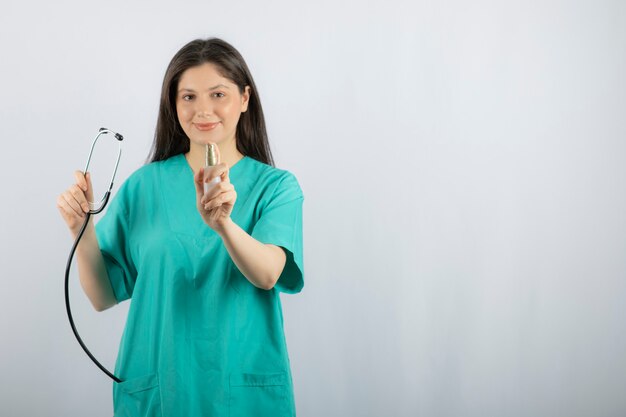 Portrait d'infirmière tenant un stéthoscope sur blanc.