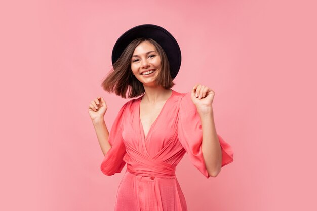 Portrait intérieur d'agréable fille glamour en robe rose. Heureuse jeune femme dansant et riant.