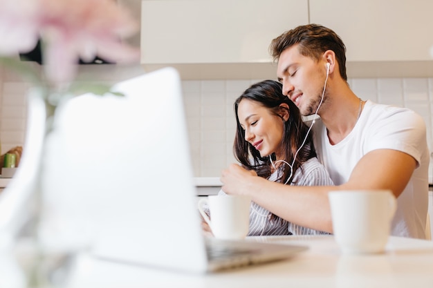 Portrait intérieur de couple marié se détendre le matin avec un ordinateur portable au premier plan