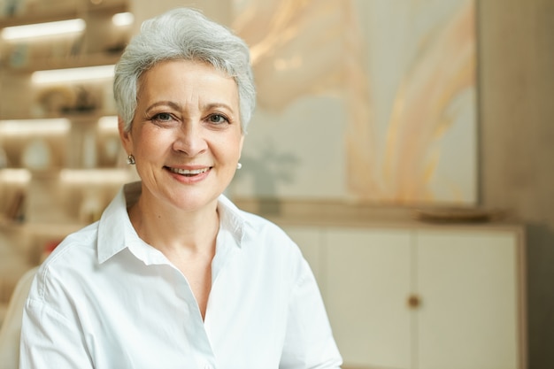 Portrait intérieur d'une femme d'affaires d'âge moyen réussie avec de courts cheveux gris travaillant à son bureau